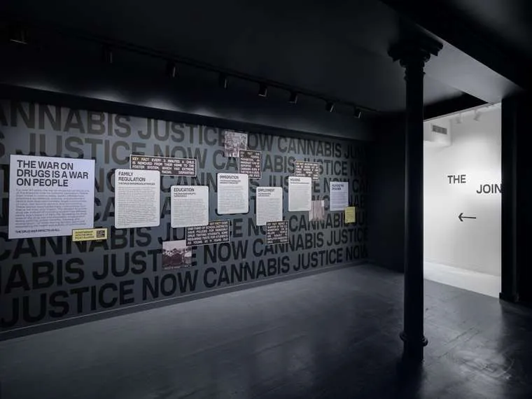 A long wall reading Cannabis Justice Now, hung with panels on the War on Drugs.
