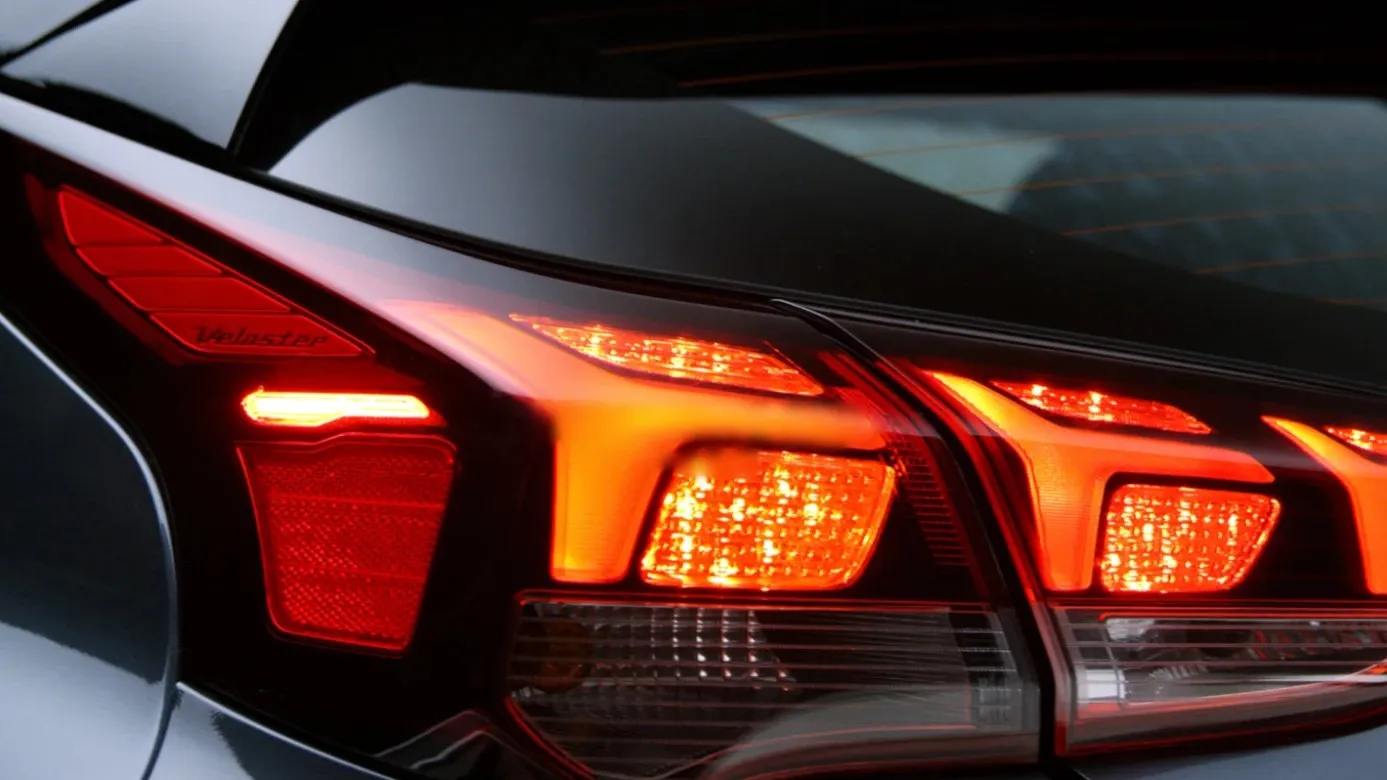 Close-up of a Hyundai Veloster's glowing red taillight on a dark grey car.