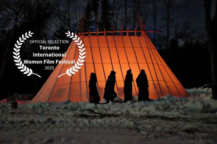 Figures in silhouette before a glowing, lit tent in a snowy forest at night.