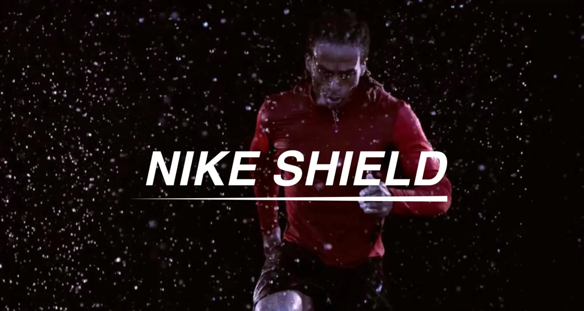 A runner in a red top sprints through falling rain on a black background, behind the words Nike Shield.